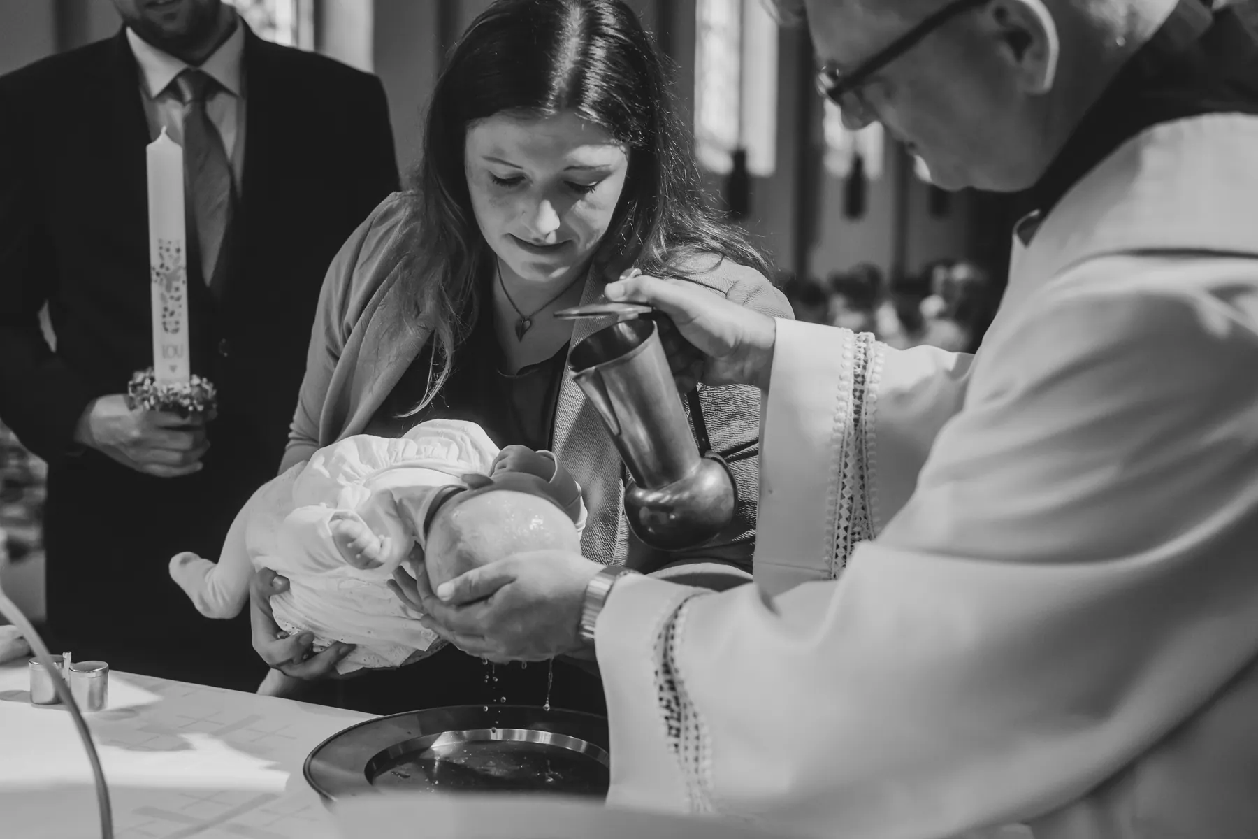 Taufe in der Kirche, der Pfarrer gießt Wasser über das Köpfchen des Babys, Schwarzweiß